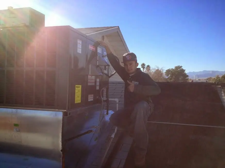 HVAC technician performing Heat Pump Repair on a rooftop unit in Bell